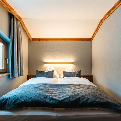 Ihre Unterkunft in St. Christoph am Arlberg: Bilder Kleines Schlafzimmer mit zwei Einzelbetten, grauen Kissen und Tagesdecke