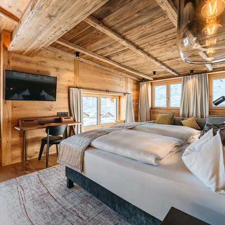 Ihre Unterkunft in St. Christoph am Arlberg: Bilder Gemütliches Holzschlafzimmer mit großen Fenstern und Bergblick
