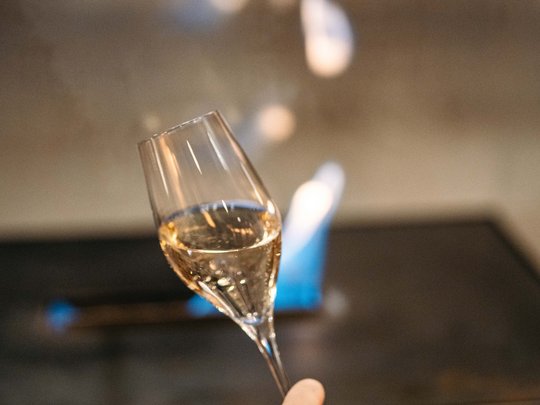 The lounge bar in your ski hotel at the Arlberg Hand holding a glass of white wine with blurred background