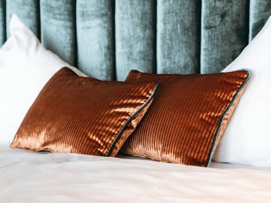 Your hotel in St. Christoph am Arlberg Two brown velvet pillows and white pillows on a bed with green headboard