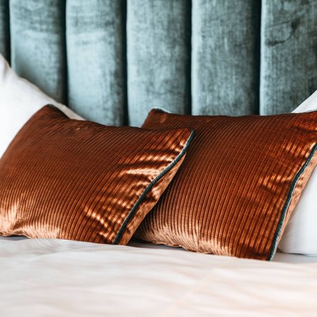 Ihre Unterkunft in St. Christoph am Arlberg: Bilder Zwei braune Samtkissen und weiße Kissen auf einem Bett vor grünem Kopfteil