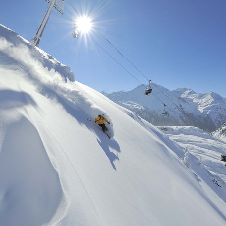 Ihre Unterkunft in St. Christoph am Arlberg: Bilder Skifahrer in gelber Jacke fährt auf verschneitem Berghang bei Sonnenschein