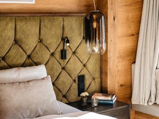 Hotel Maiensee: your hotel in St. Christoph Cozy bedroom with green upholstered headboard and wooden walls.
