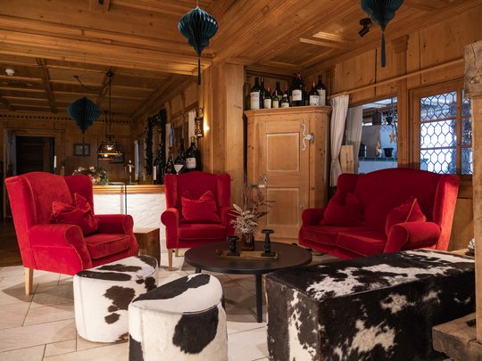 Your hotel in St. Christoph am Arlberg Rustic living area with red armchairs and cowhide stools in wooden cabin