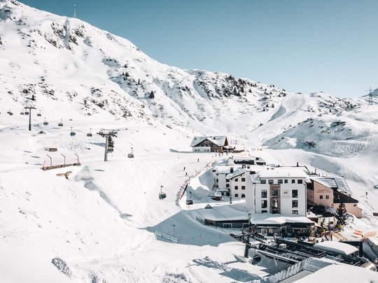 Arlberg: Ihr Hotel an der Piste Schneebedecktes Skigebiet mit Sesselliften und Gebäuden unter klarem Himmel