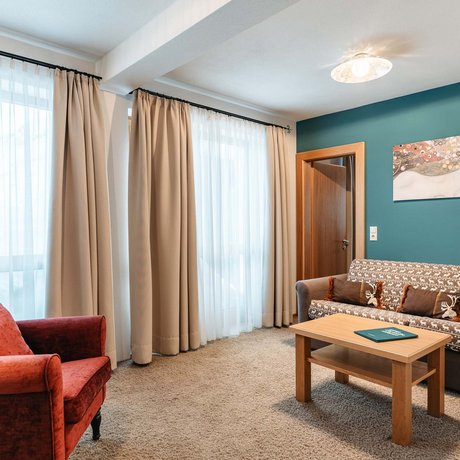 Ihre Unterkunft in St. Christoph am Arlberg: Bilder Gemütliches Wohnzimmer mit rotem Sessel, Sofa, Holzttisch und Kunst an der Wand