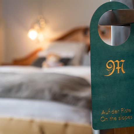 Ihre Unterkunft in St. Christoph am Arlberg: Bilder Türhänger mit Schrift Auf der Piste an einem Zimmertürgriff im Hotelzimmer