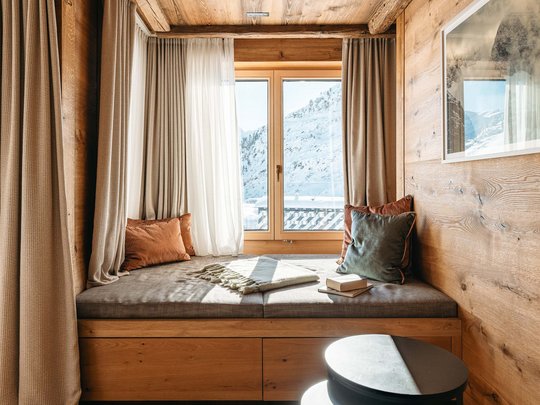 Hotel Maiensee: your hotel in St. Christoph Cozy window seat with cushions and view of snowy mountains outside