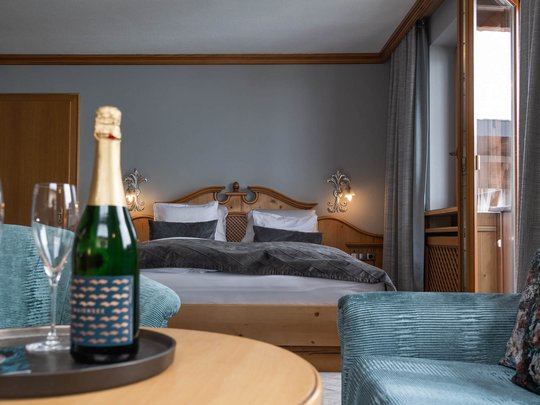 Your hotel in St. Christoph am Arlberg Hotel room with double bed, armchair, and champagne on table