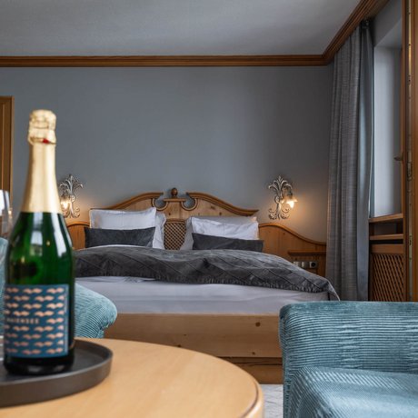 Ihre Unterkunft in St. Christoph am Arlberg: Bilder Hotelzimmer mit Doppelbett, Sessel und Champagner auf Tisch