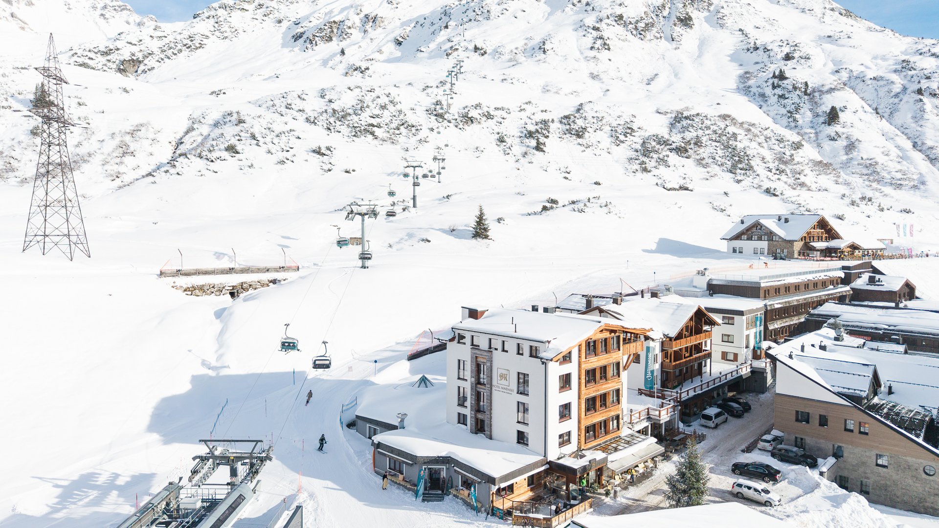 Zum Pressebereich des Hotel Maiensee Schneebedeckte Alpenlandschaft mit Skilift und Gebäuden am Fuße des Berges