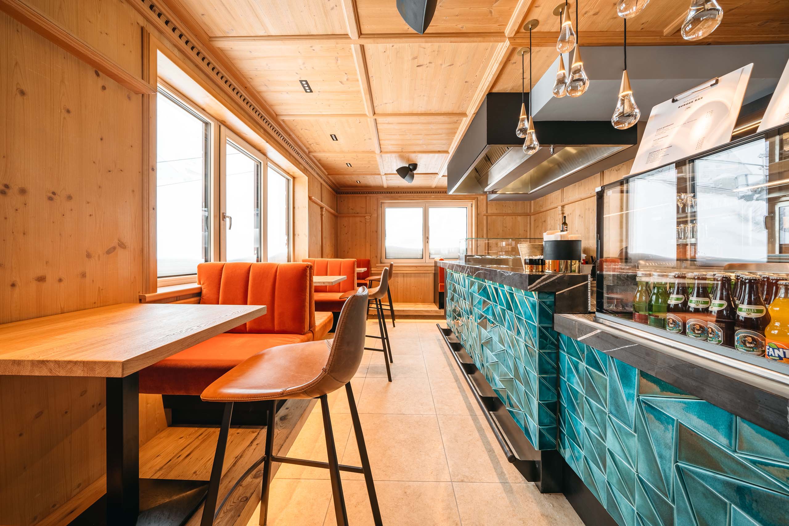 Premium burgers at the ski hotel near St. Anton am Arlberg Interior of a modern bar with orange seating and blue tiled counter