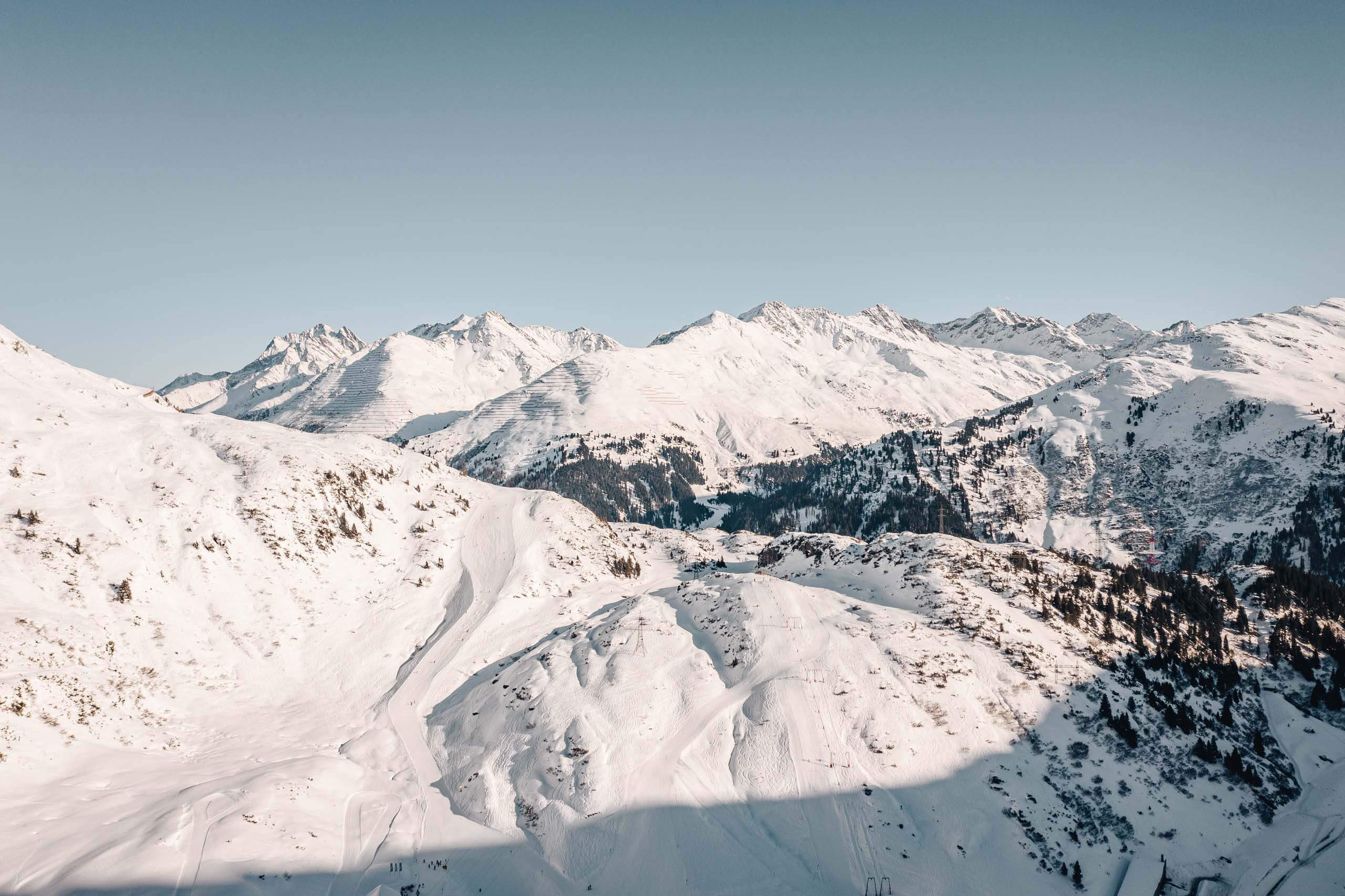 Arlberg: Ihr Hotel an der Piste Schneebedeckte Gipfel in den Alpen unter klarem Himmel
